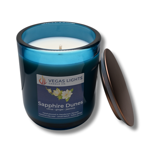 Blue candle jar with a white candle inside, featuring the Vegas Lights Candle Co. logo and product name 'Sapphire Dunes' on a white background.