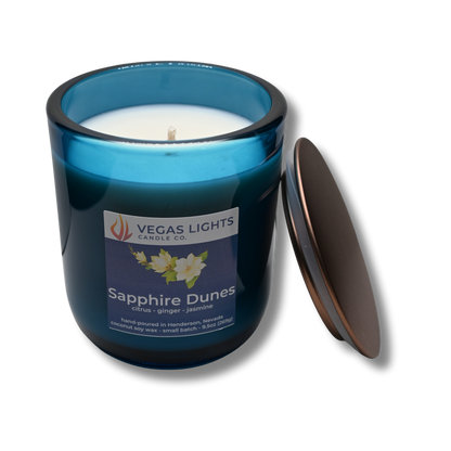 Blue candle jar with a white candle inside, featuring the Vegas Lights Candle Co. logo and product name 'Sapphire Dunes' on a white background.